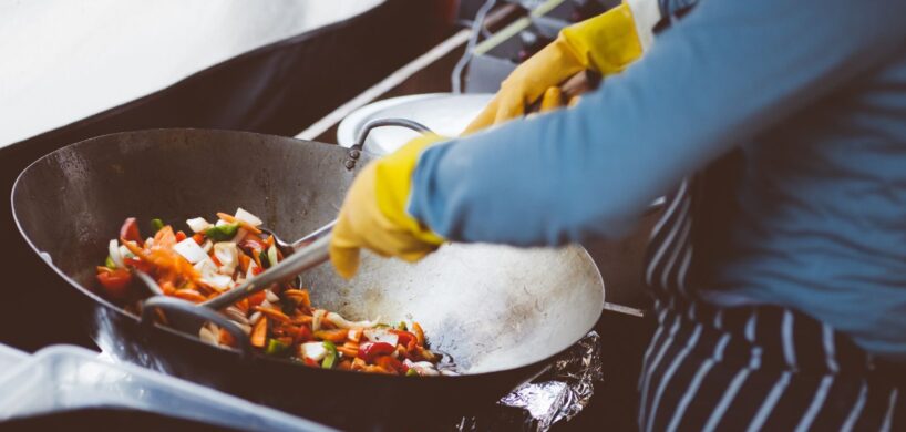 A chef stir-frying vegetables in a wok, showcasing vibrant fresh ingredients.